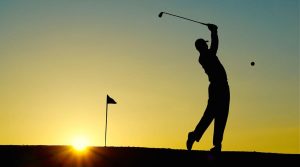 un golfista in controluce al tramonto che gioca a golf