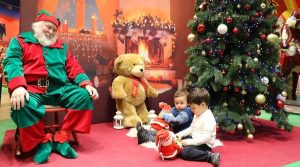 babbo natale seduto che guarda due bambini giocare