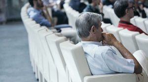 un uomo che ascolta uno spettacolo seduto su poltrone bianche