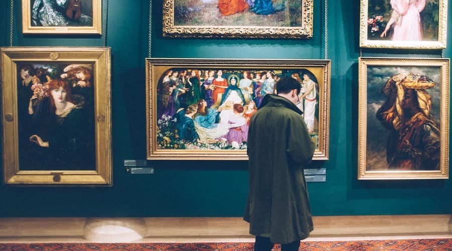 un uomo di spalle ad una mostra di quadri