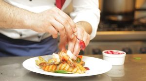 le mani di uno chef che cucina del pesce