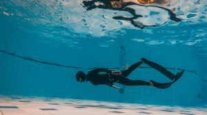 Deep dive under a swimming pool with a diver exploring the underwater world.