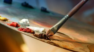 Vibrant artist palette with paint and brush creating colorful artwork.